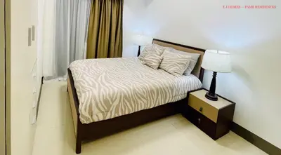 a bedroom with a bed and a night stand with a lamp at EJ Homes - Fame Residences in Manila