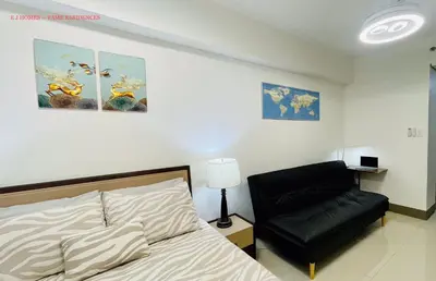 a bedroom with a bed and a black chair at EJ Homes - Fame Residences in Manila