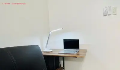 a laptop computer sitting on a desk with a lamp at EJ Homes - Fame Residences in Manila