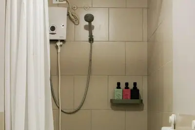 a shower in a bathroom with two bottles of alcohol at Serenity Suites: Your tranquil gateway! in Biñan