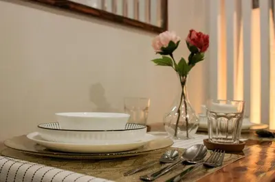 a table with plates and bowls and a vase of flowers at Serenity Suites: Your tranquil gateway! in Biñan