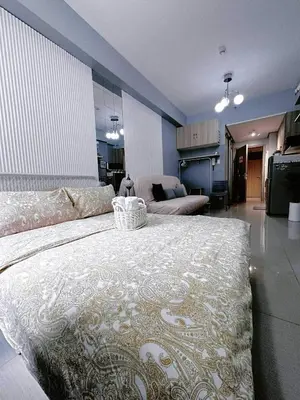 a bedroom with a large bed and a living room at Homestay Manila Mall of Asia Shore Residences at TresMarias' in Manila