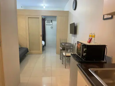 a kitchen with a microwave and a living room at Jazz Residences Makati City by darpm in Manila