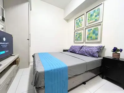 a bedroom with a bed and a flat screen tv at KL Tower Makati near AIM, Greenbelt 90mbps WIFI in Manila