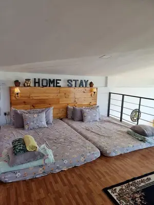 two beds in a room with a home stay sign on the wall at Dicimulacion Staycation House in Angono