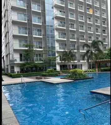 a large blue swimming pool in front of a large building at Cozy Studio Flat Near Airport in Manila
