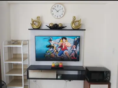 a flat screen tv sitting on a wall with a clock at Pasay Staycation with Parking Space in 150 Newport Boulevard near Resort World & NAIA T3 in Manila