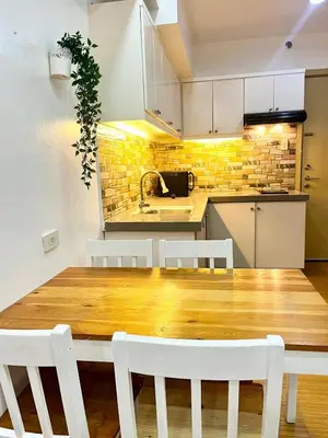 a kitchen with a wooden table and white chairs at Comfy Condo near BGC, Makati and Naia in Manila