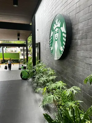 a sign on the side of a brick building with plants at Comfy Condo near BGC, Makati and Naia in Manila