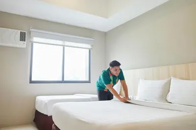 a man standing between two beds in a room at Hotel101 - Fort in Manila