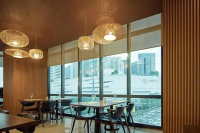 a restaurant with tables and chairs and large windows at Hotel101 - Fort in Manila