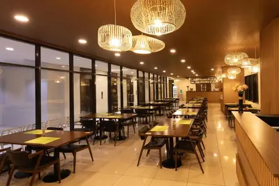 a restaurant with tables and chairs and chandeliers at Hotel101 - Fort in Manila