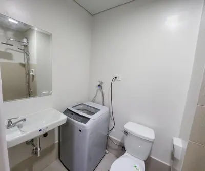 a white bathroom with a toilet and a sink at Bloom Residences Condo 2Br in Manila