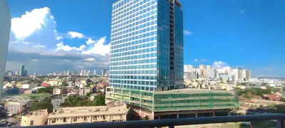 a tall glass building with a city in the background at Aveline Suites Executive City View ACQUA Private Residences near Rockwell Makati in Manila
