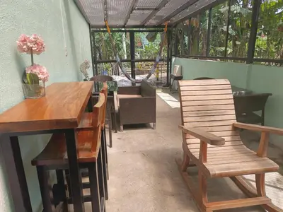 a patio with wooden chairs and a table and a couch at Misty Hills Guesthouse Amadeo - Tagaytay in Amadeo