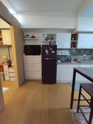 a kitchen with a black refrigerator and white cabinets at Maicozy condo in Manila