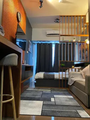 a bedroom with a bed and a couch and a table at Cozy Crib @ Air Residences - Makati in Manila