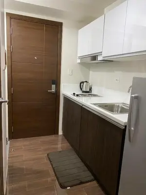 a small kitchen with a sink and a refrigerator at Cozy Crib @ Air Residences - Makati in Manila
