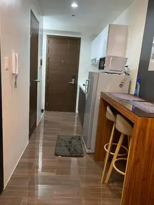 a small kitchen with a counter and a refrigerator at Cozy Crib @ Air Residences - Makati in Manila