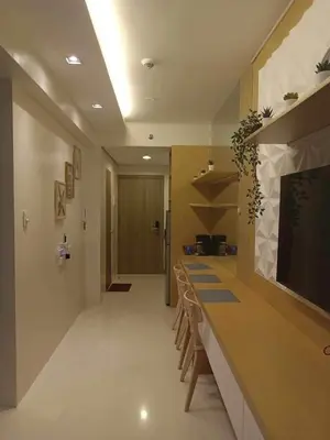 a room with a long bar with chairs and a television at Coast Residences Penthouse with skyline and manila bay view in Manila