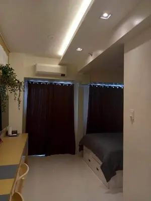 a bedroom with a bed and a desk and curtains at Coast Residences Penthouse with skyline and manila bay view in Manila