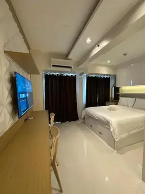a bedroom with a bed and a desk with a television at Coast Residences Penthouse with skyline and manila bay view in Manila