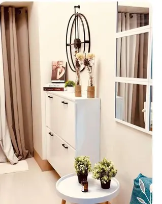 a room with a white cabinet and a table with flowers at Shore 3 Residences MOA Manila in Manila