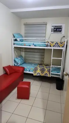 a room with three bunk beds and a red couch at URBAN DECA O1257 Ortigas near SM EAST PASIG in Manila
