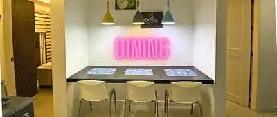 a dining room table with chairs and a pink neon sign at Family Room Affordable, Cheapest Deluxe Double Unit in Manila with 2 Balconies & 2 Bathrooms 25 Percent Discount, Free Sauna & Pool Access Near Manila Bay, Robinsons Place Ermita, Pgh, Bellagio, UP, Pedrogil, US Embassy, NAIA Airport Updated 2024 in Manila