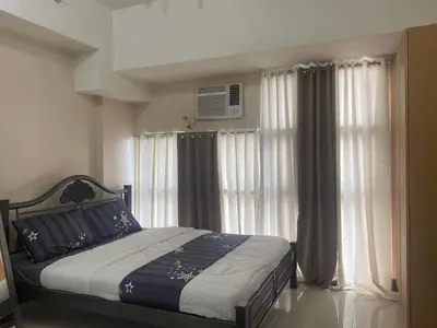 a bedroom with a bed and windows with curtains at Condotel in Venice Grand Canal Mall Taguig in Manila