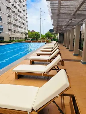 a row of lounge chairs next to a swimming pool at Acellyne's Suites at Green 2 Residences with Netflix! in Dasmariñas