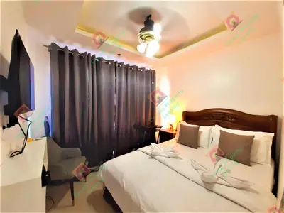 a bedroom with a bed with a black curtain and a chair at BirchTower Studio Condo with Balcony & Pool - Carosa Staycation in Manila
