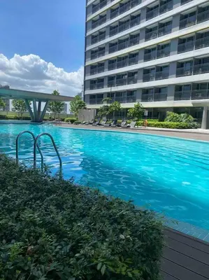 a large blue swimming pool in front of a building at Modern 1-BR Condo Unit in Manila