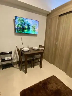 a dining room with a table and a tv on the wall at Modern 1-BR Condo Unit in Manila