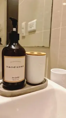 a bottle of soap and a cup on a bathroom sink at Luxe Bonifacio Global City Taguig Uptown Condo Hotel 1 BR Suite in Manila
