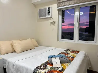 a bedroom with a bed and a window with the sunset at Staycation Condotel Room To Stay in Manila