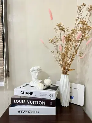 a stack of books sitting on a table with a vase at Staycation Condotel Room To Stay in Manila
